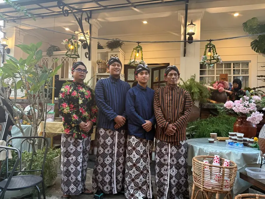 Empat anggota tim Pojoke Segara berpakaian adat Jawa berdiri di teras kafe
