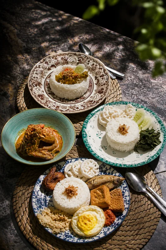 Aneka nasi dan lauk khas Nusantara di atas piring motif klasik