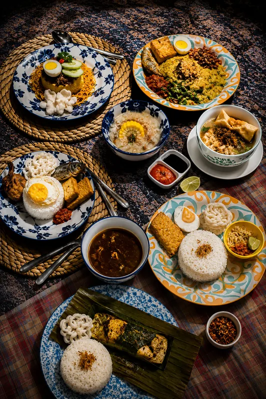 Hidangan nasi dengan aneka lauk dan sambal di atas anyaman rotan